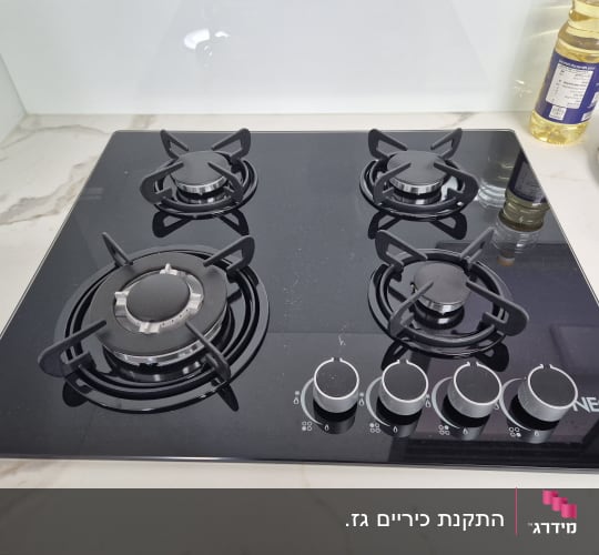 כיריים גז שחורות עם ארבעה מבערים וכפתורי שליטה